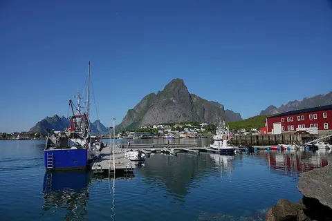 Reine 港湾停泊的渔船与码头，远处为 Olstinden 山峰