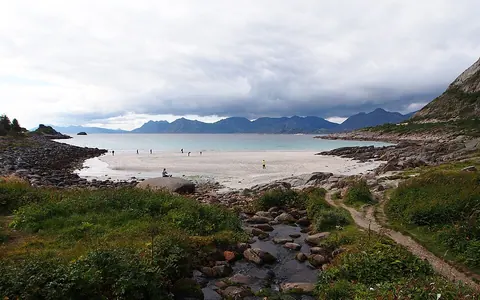 Rørvikstranda 白沙湾、浅海与远山，前景有溪流和岩石